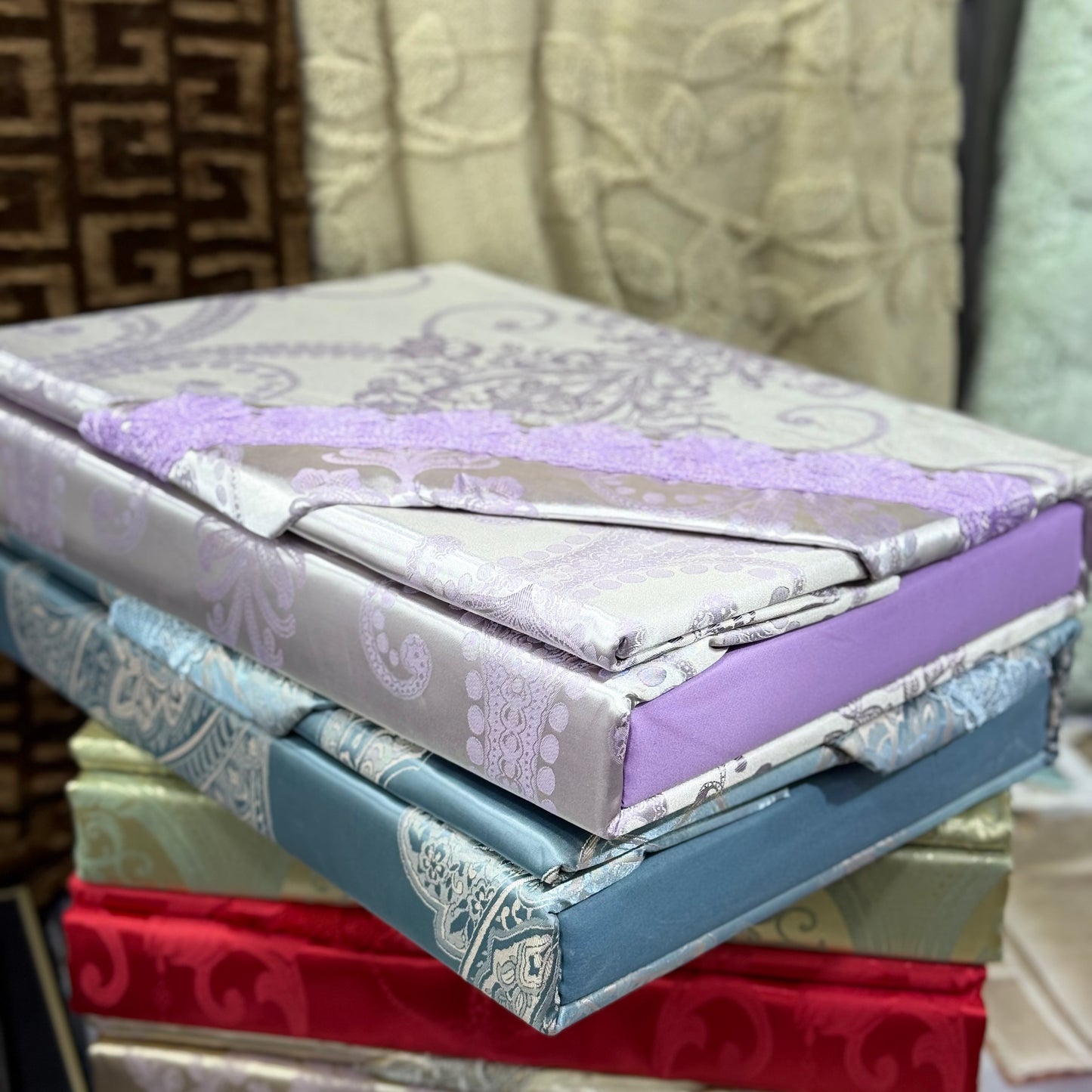 Stack of patterned fabric sheets with a decorative border.