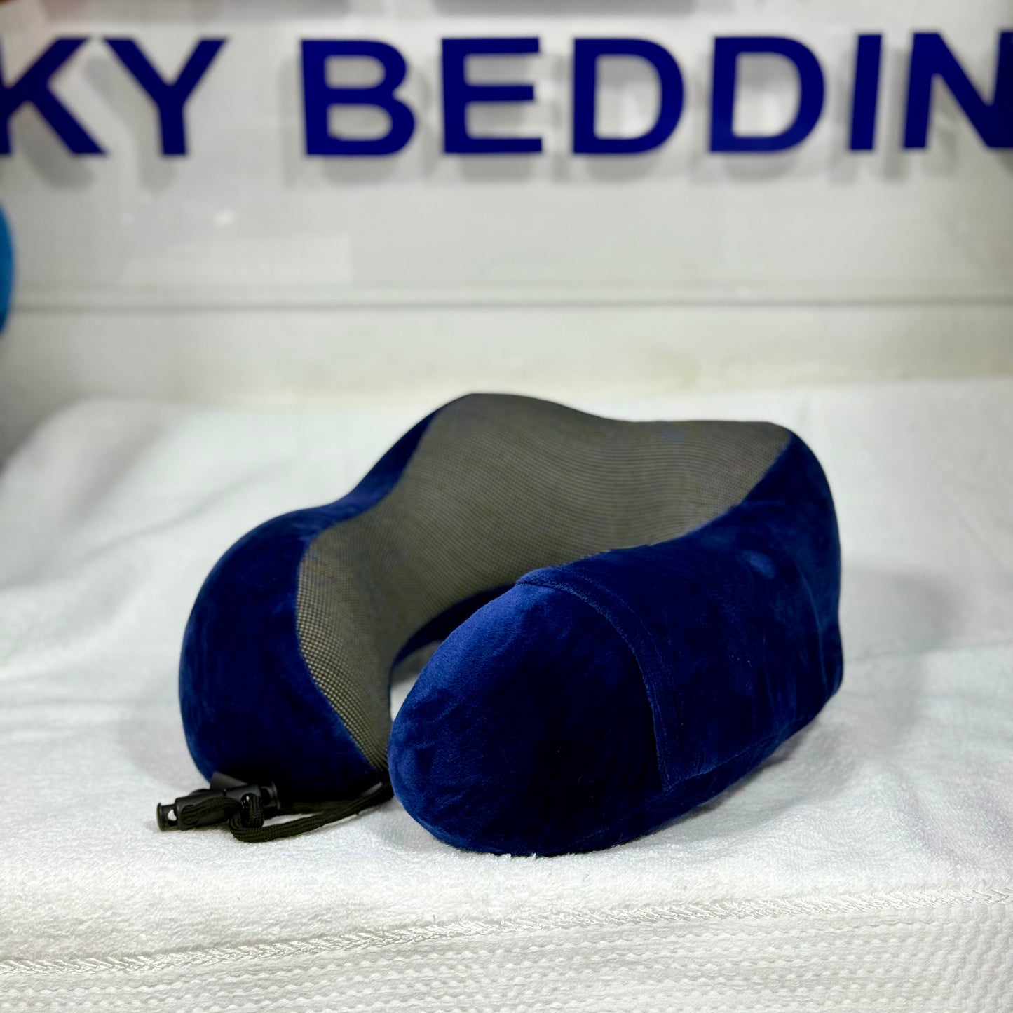 Blue travel pillow on a white surface with 'WICKY BEDDING' branding in the background.