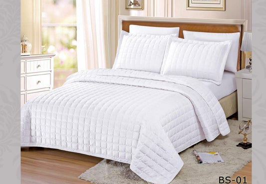 White quilt and pillow set on a bed in a bedroom setting